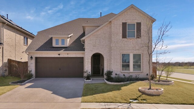 view of front facade with brick siding, a shingled roof, a garage, a front lawn, and concrete driveway