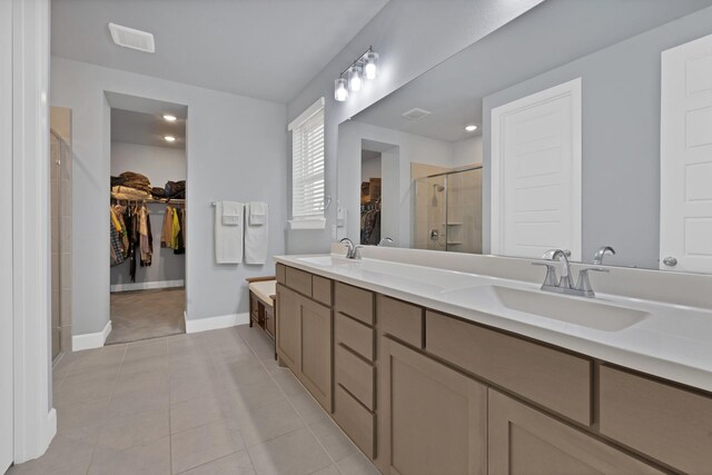 bathroom featuring tile patterned floors, a shower stall, double vanity, and a sink