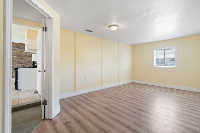 7918 Racine Dr, Dallas, TX 75232 - empty room with light wood finished floors, visible vents, a textured ceiling, and baseboards