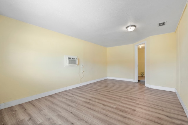 7918 Racine Dr, Dallas, TX 75232 - empty room with a wall unit AC, baseboards, visible vents, and light wood finished floors