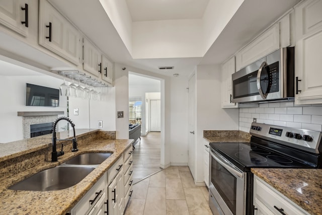 3105 San Jacinto St Unit 304, Dallas, TX 75204 - kitchen with appliances with stainless steel finishes, a fireplace, tasteful backsplash, and white cabinets