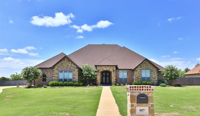 957 Caballo Dr, Abilene, TX 79602 - french country home featuring a front yard, brick siding, fence, and a shingled roof