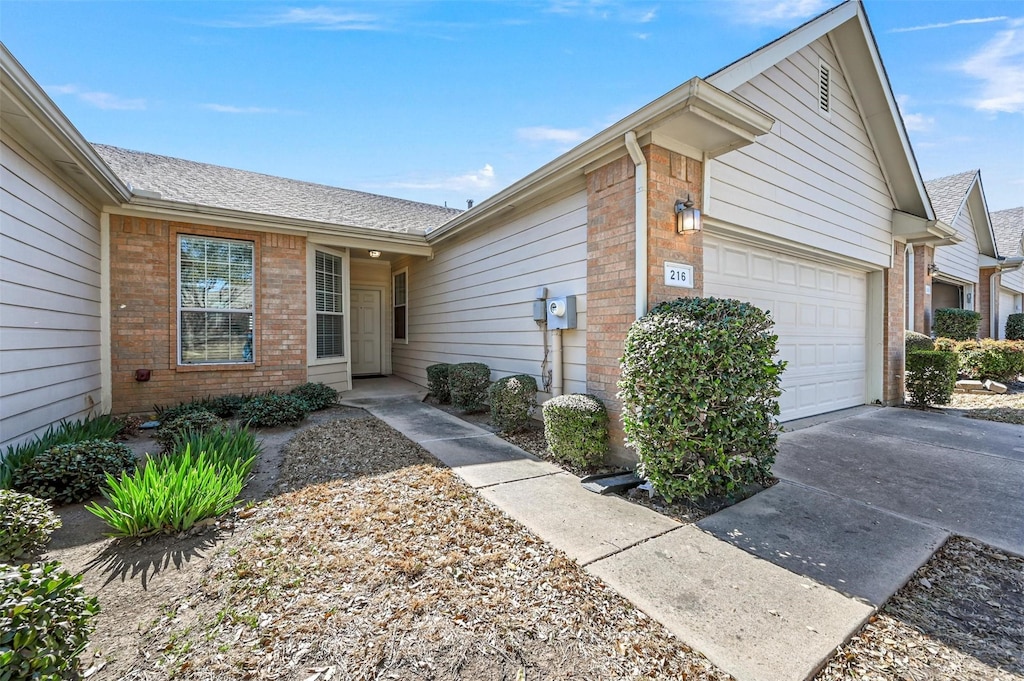 view of front of house with concrete driveway, an attached garage, and brick siding