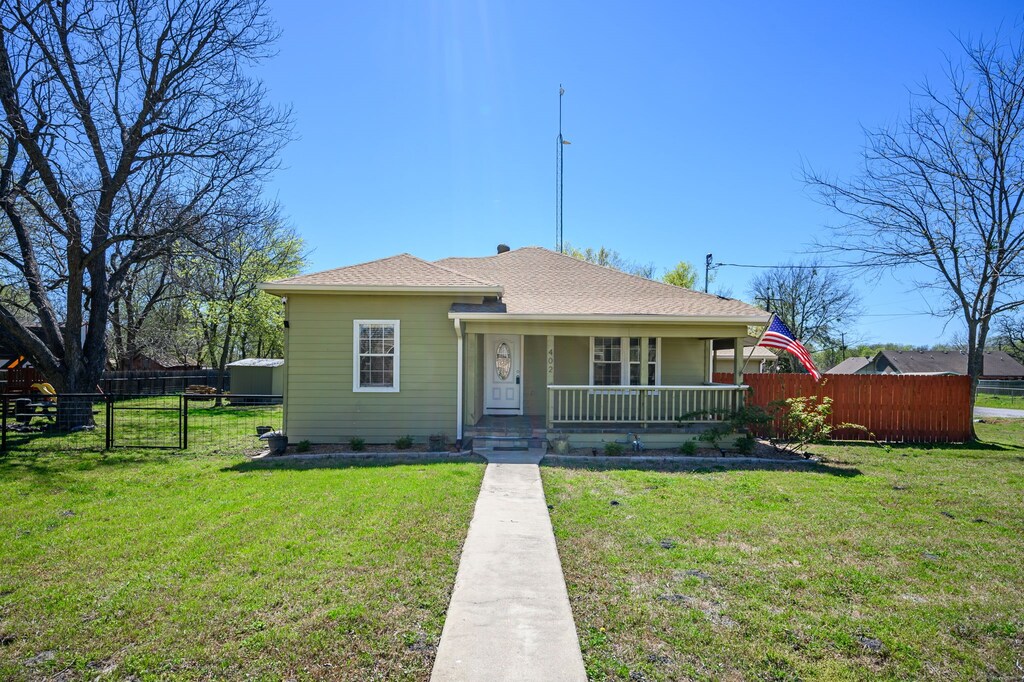 402 Collin St, Nevada, TX 75173 - bungalow-style house with covered porch, fence, and a front lawn