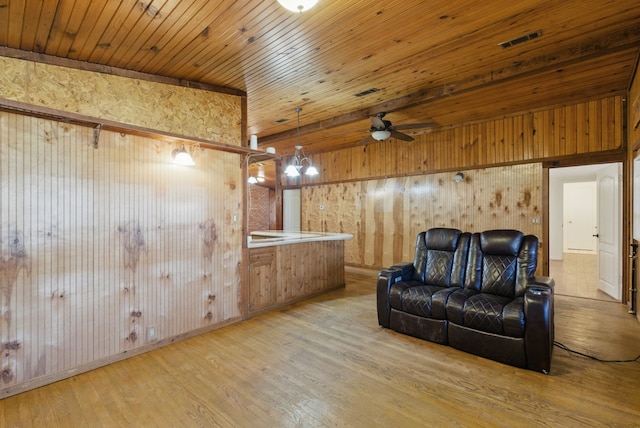 living area featuring visible vents, wood walls, wood ceiling, wood finished floors, and a ceiling fan
