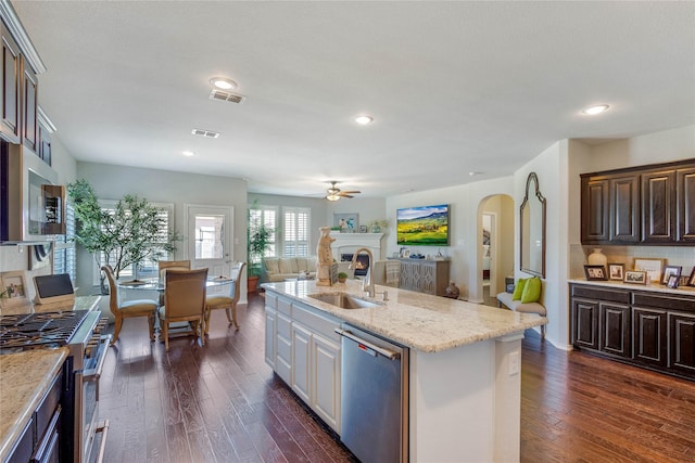 108 Oakmont Dr, Argyle, TX 76226 - kitchen featuring a sink, dark wood-style floors, open floor plan, arched walkways, and appliances with stainless steel finishes