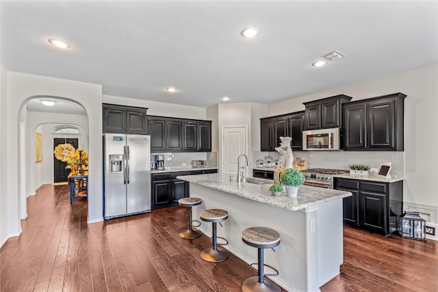 108 Oakmont Dr, Argyle, TX 76226 - kitchen featuring stainless steel appliances, arched walkways, dark wood-style floors, and dark cabinets