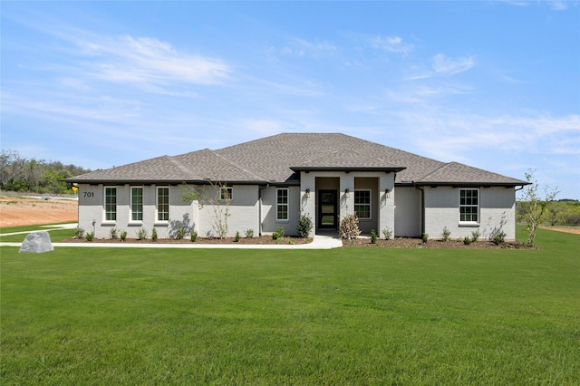 prairie-style house featuring a shingled roof, brick siding, and a front lawn