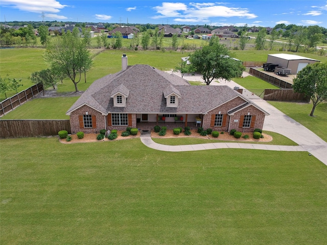view of front facade featuring brick siding, a fenced backyard, a chimney, and a shingled roof