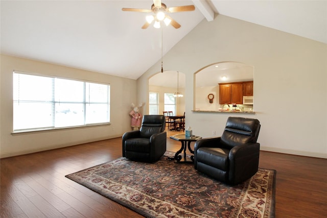 living area featuring beam ceiling, wood finished floors, arched walkways, and a ceiling fan