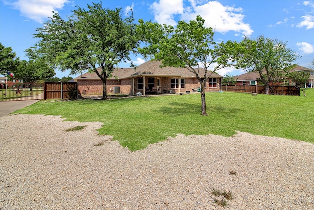 exterior space with a gate, fence, a shingled roof, a yard, and brick siding