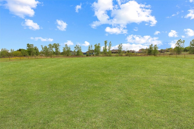 view of yard with fence and a rural view