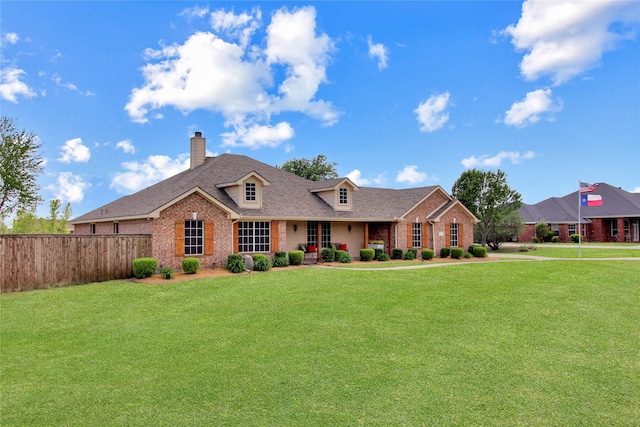 view of front facade featuring brick siding, a front lawn, and fence