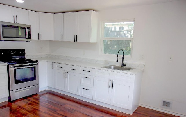 711 Dubois St, Denison, TX 75020 - kitchen featuring dark wood finished floors, white cabinets, stainless steel appliances, and a sink