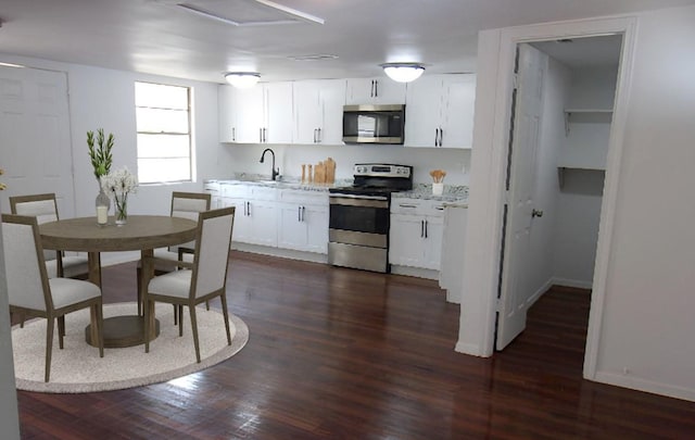 711 Dubois St, Denison, TX 75020 - kitchen featuring baseboards, appliances with stainless steel finishes, dark wood-style floors, white cabinets, and a sink