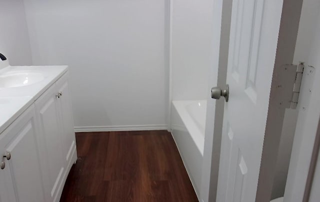 711 Dubois St, Denison, TX 75020 - bathroom with vanity, wood finished floors, baseboards, and a washtub