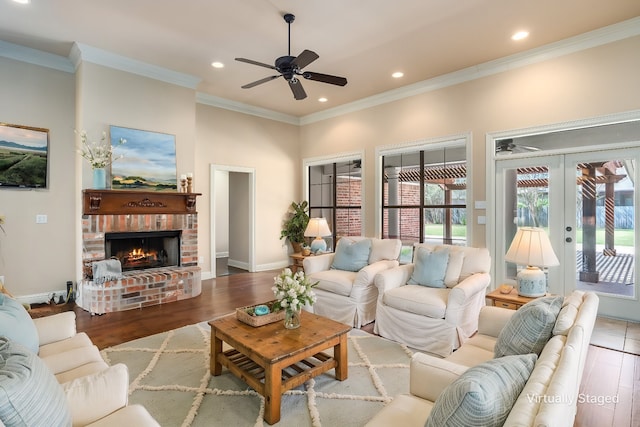 living room featuring a ceiling fan, recessed lighting, ornamental molding, a brick fireplace, and wood finished floors