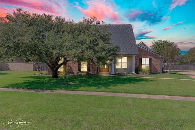 view of front of house with a front yard, brick siding, and fence