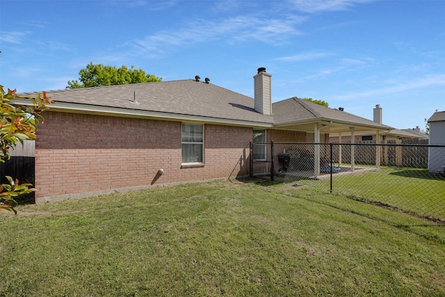 rear view of house featuring fence, a chimney, a yard, and brick siding