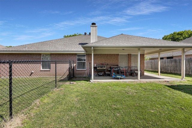 back of house featuring a lawn, a chimney, a fenced backyard, and a patio area