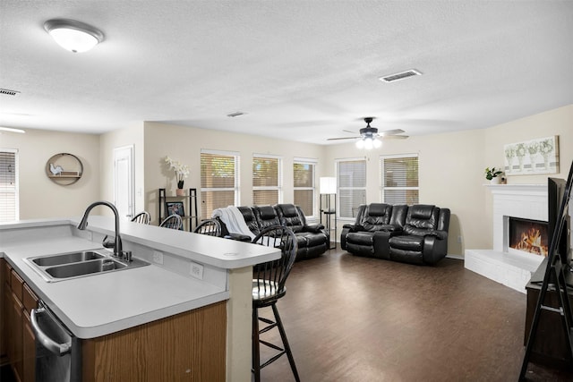 kitchen featuring visible vents, ceiling fan, a kitchen breakfast bar, and a sink