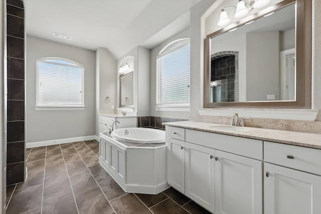 bathroom featuring a garden tub, baseboards, and two vanities