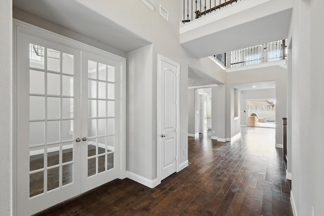 foyer entrance with french doors, baseboards, a towering ceiling, and dark wood-style flooring