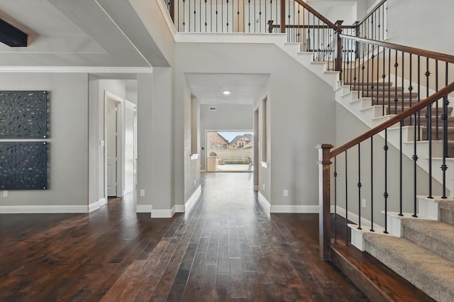 entrance foyer with wood-type flooring, baseboards, stairway, and a towering ceiling