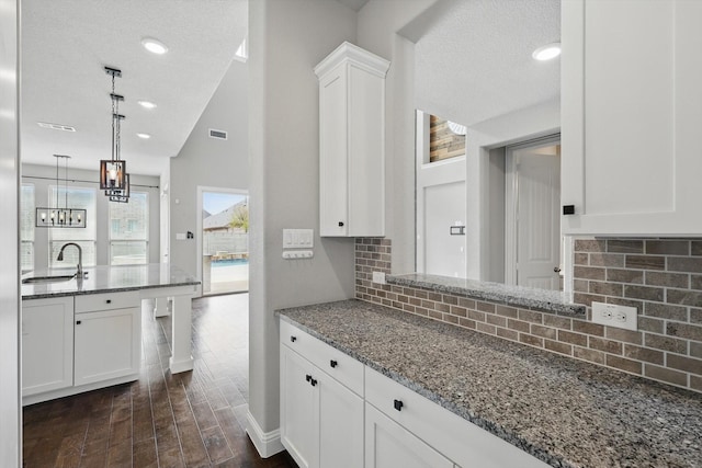 kitchen featuring a sink, white cabinets, stone countertops, and a textured ceiling