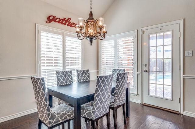 dining space featuring an inviting chandelier, lofted ceiling, dark wood-type flooring, and baseboards