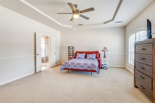 bedroom featuring a tray ceiling, visible vents, and light carpet