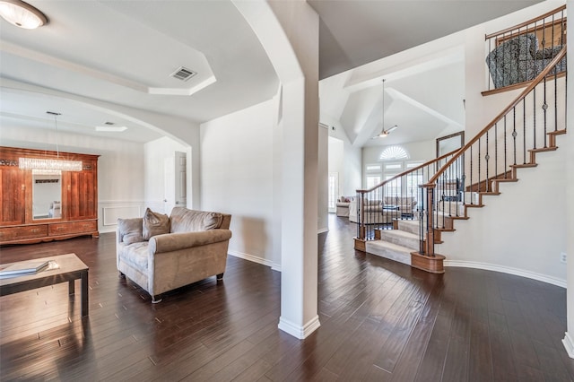 living area with arched walkways, stairway, visible vents, and baseboards