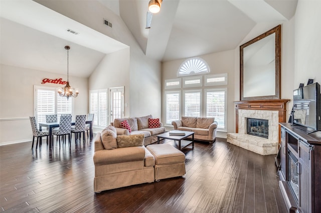 living area featuring dark wood finished floors, visible vents, a notable chandelier, high vaulted ceiling, and a fireplace