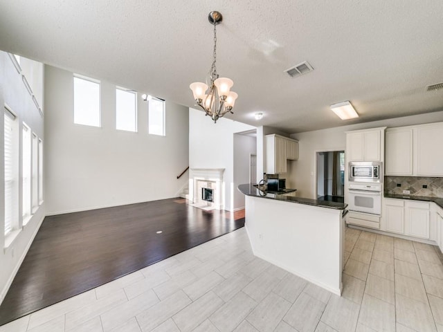 8317 Spring Valley Ln, Plano, TX 75025 - kitchen with white oven, stainless steel microwave, dark countertops, and visible vents