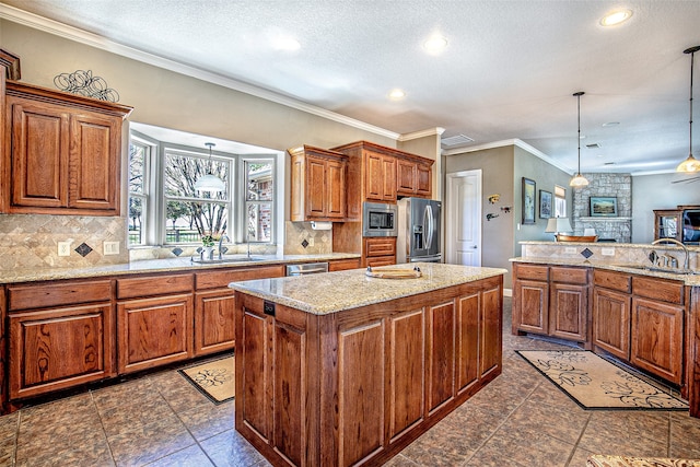 kitchen featuring appliances with stainless steel finishes, a sink, a center island, brown cabinetry, and recessed lighting