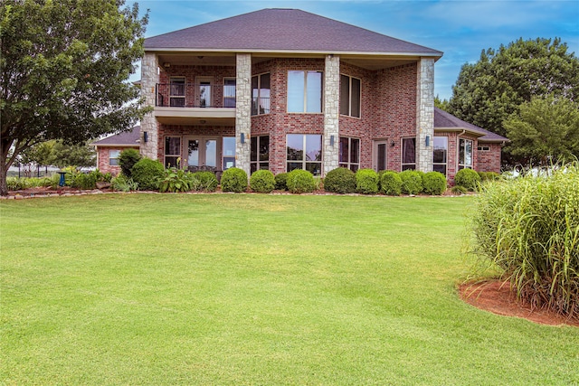 rear view of house featuring a lawn, brick siding, and a balcony