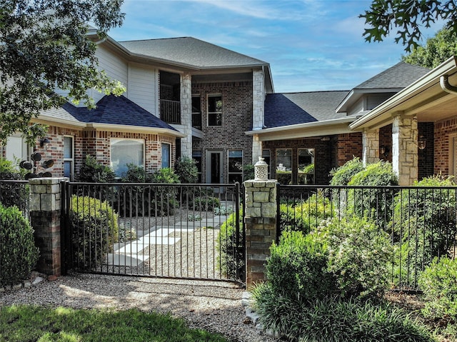 view of front of house featuring brick siding, roof with shingles, and fence