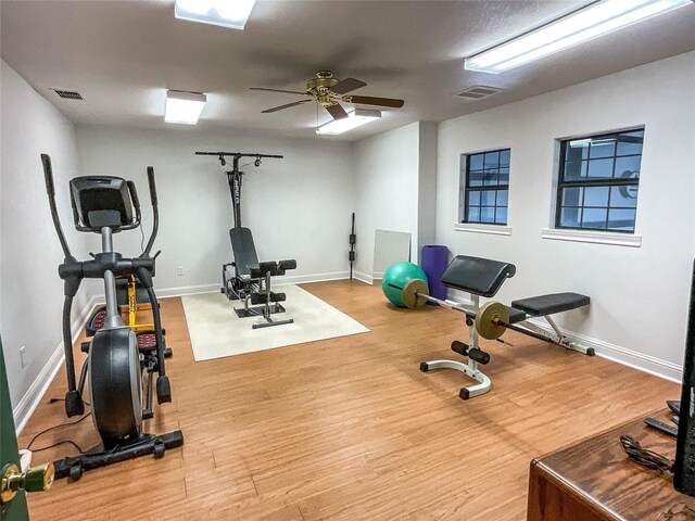 workout room with baseboards, wood finished floors, and a ceiling fan