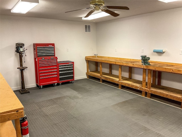 misc room with a workshop area, a ceiling fan, dark colored carpet, and baseboards