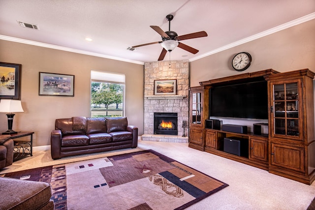 carpeted living room with a ceiling fan, a stone fireplace, crown molding, and baseboards