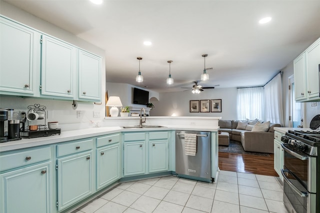 kitchen with a peninsula, appliances with stainless steel finishes, ceiling fan, a sink, and open floor plan