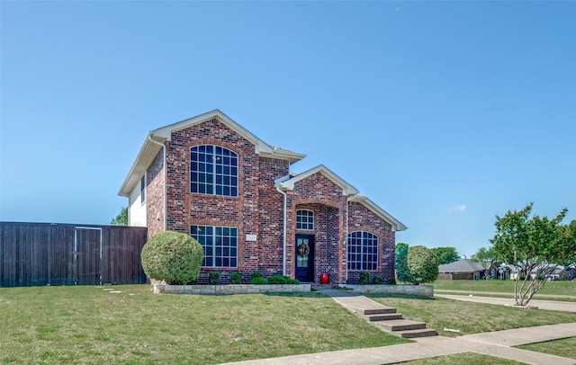 traditional-style home with a front yard, brick siding, and fence