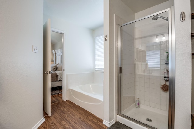 full bath featuring wood finished floors, a shower stall, ensuite bath, and a garden tub