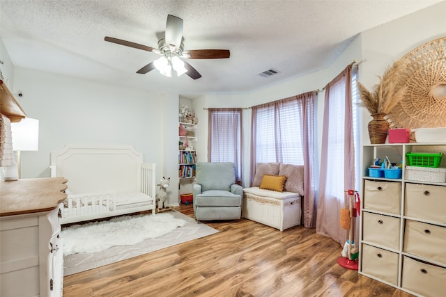 bedroom featuring visible vents, wood finished floors, ceiling fan, and a textured ceiling