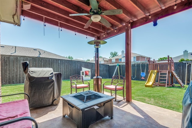 view of patio / terrace featuring an outdoor fire pit, ceiling fan, a fenced backyard, and a playground