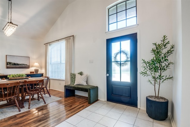 entryway with baseboards, high vaulted ceiling, a wealth of natural light, and light wood-style flooring