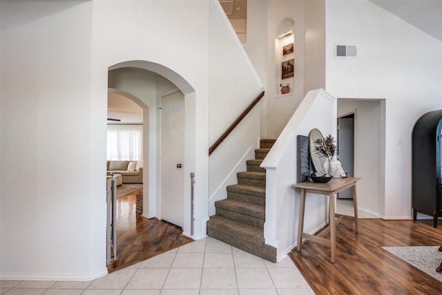stairs with a towering ceiling, visible vents, arched walkways, and baseboards