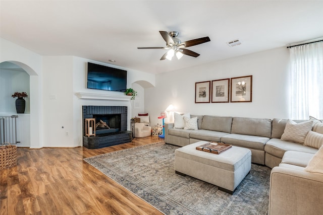 living area with wood finished floors, visible vents, ceiling fan, and arched walkways
