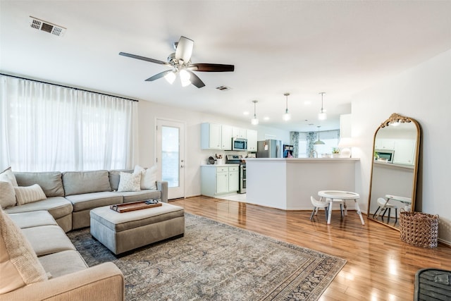 living area featuring a ceiling fan, visible vents, and light wood-type flooring
