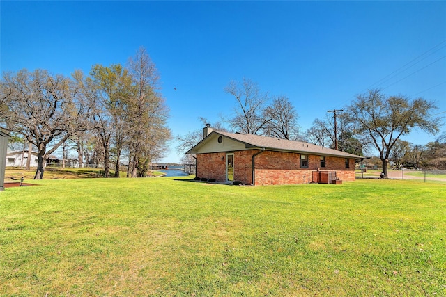 view of side of home with brick siding, fence, a lawn, and a chimney